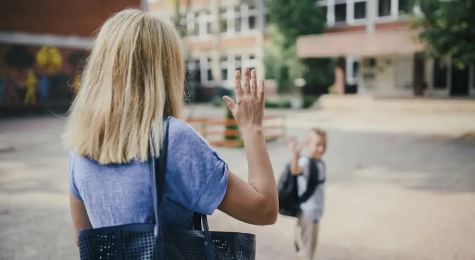 Ubezpieczenie NNW dla ucznia i przedszkolaka - matka z synem pod szkołą machają do siebie na pożegnanie